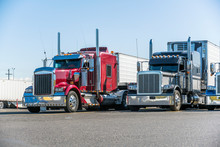 Classic Bonnet Big Rigs Semi Trucks With Reefer Semi Trailers Standing In Row On Truck Stop Parking Lot Waiting For Delivery Schedule