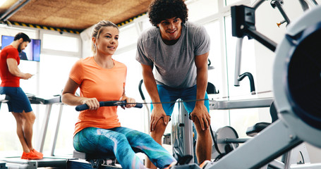 Wall Mural - Young beautiful woman doing exercises with personal trainer