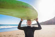 © Daniel - happy senior with surftable on his head is smiling and laughing - old and mature man having fun surfing with a black wetsuits - active retired adult doing activity alone