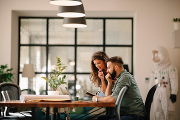 Wall Mural - Colleagues in office. Businesswoman and businessman discussing work in office. Two friends in working together.  