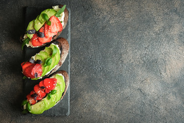 Wall Mural - Toast or sandwich with avocado, cheese, strawberries, herbs and seeds on a dark background. An idea for bruschetta or for a healthy snack. Healthy vegan breakfast.Top view. Copy space.