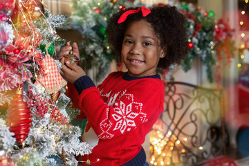 Wall Mural - Beautiful little black girl decorating Christmas tree