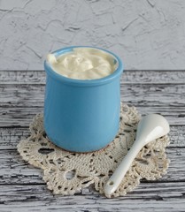 Sour cream in a blue wine glass stands on a wooden table. Napkin and spoon.