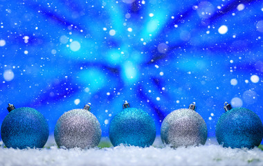 Wall Mural - Abstract Christmas background,New Year and Christmas background. Blue and white Christmas toys lie on the snow, with a bright background. Falling snow.