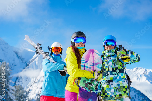 Dekoracja na wymiar  sportowcy-i-kobieta-ze-snowboardem-i-nartami-stojacymi-w-osrodku-snieznym-na-tle-gory