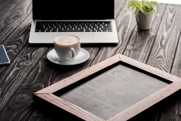 Poster - selective focus of chalk board near cup of coffee and laptop on table, e-commerce concept