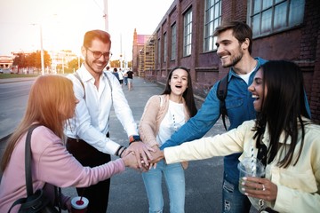 Group of friends stacking hands outdoor - Happy young people having fun joining and celebrating together