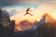 canvas print picture - Man jumping between mountains at sunset.