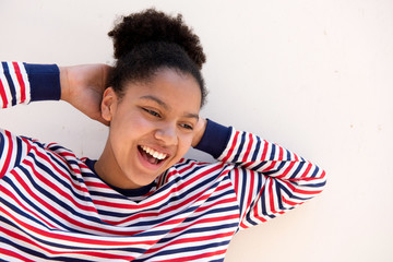 portrait of african american girl laughing with hands behind head against white background