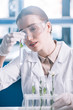 © LIGHTFIELD STUDIOS - selective focus of attractive biochemist in goggles holding test tube with green plant