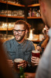 © chika_milan - Group of friends drinking beer, chatting and having good time at pub. Night out.