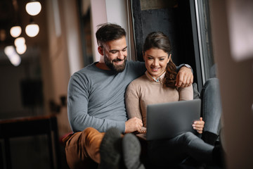 Wall Mural - Young happy couple. Boyfriend and girlfriend using laptop together. 