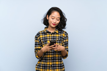 Asian young woman over isolated blue background sending a message with the mobile