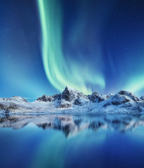 Wall Mural - Mountains and northern lights in the sky. Reflections of the night sky and mountains on the water. Winter landscape in Norway