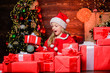 © be free - Santa brought me gifts. Child happy excited girl find gifts near christmas tree. Happiness and joy. Merry christmas. Happy childhood concept. Kid wear santa hat hold wrapped christmas gift box