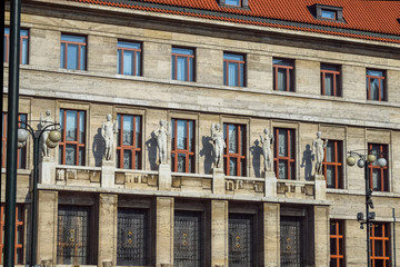 Wall Mural - Sculptures of naked people over the entrance to the building with a shadow on the wall