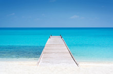 Wooden Bridge Or Pier On Tropical White Sand Beach With Clear Blue Sea And Sky On Sunny Day. Boardwalk Into The Ocean And Turquoise Water. Summer Holidays Background With Copy Space. Kuramathi Island.