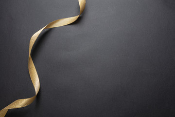 Wall Mural - golden ribbon curl on black color background. minimal card template