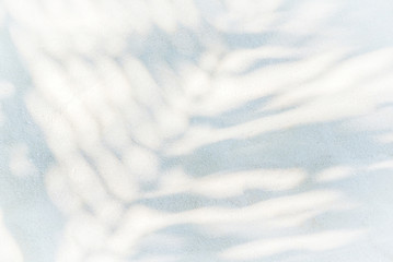 Flat lay or top view of shadows palm leaf on white sand beach texture background. Minimal summer concept with palm tree leaf. Backdrop for mockups and creative advertising, copy space.