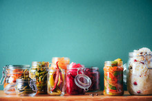 Assortment Of Various Fermented And Marinated Food Over Wooden Background, Copy Space. Fermented Vegetables, Sauerkraut, Pepper, Garlic, Beetroot, Korean Carrot, Cucumber Kimchi In Glass Jars.