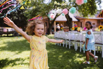 Small girl running outdoors in garden in summer, birthday celebration concept.