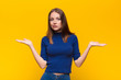 © kues1 - young red head woman feeling puzzled and confused, doubting, weighting or choosing different options with funny expression against flat wall