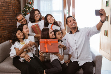 Wall Mural - big family selfie on christmas day. asian people take picture using mobile phone