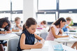 © Halfpoint - Concentrated small school children sitting at the desk in classroom, writing.