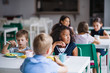 © Halfpoint - A group of cheerful small school kids in canteen, eating lunch.