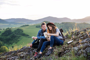 Wall Mural - young tourist couple travellers sitting in nature, resting after hiking.