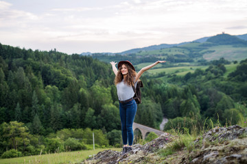 Wall Mural - young tourist woman hiker with backpack standing in nature, resting.