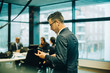 © Maskot - Side view of businessman talking on mobile phone through headphones in office