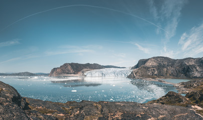 Wall Mural - Panoramic image of Eqip Sermia, Eqi Glacier in Greenland Disko Bay. Boat trip in the morning over the arctic sea,Baffin Bay, calving glacier. Ice breaking of on a blue sky wth clouds.