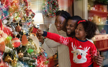 Happy Black Family Of Three Decorating Christmas Tree At Home