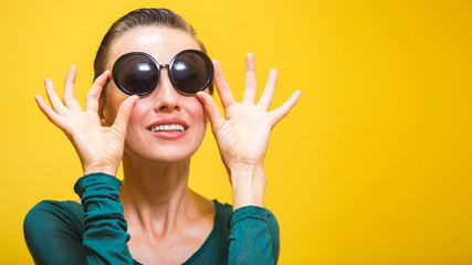 Wall Mural - Stylish woman in sunglasses isolated over yellow background