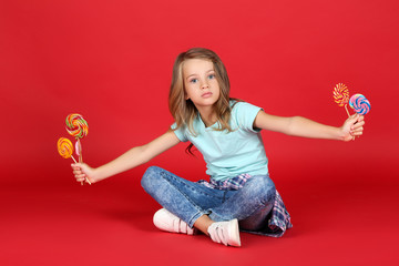 Wall Mural - Young girl with colorful lollipops on red background