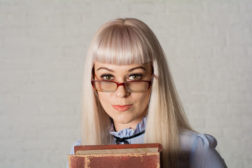 A beautiful woman with glasses and long hair, holding a book.