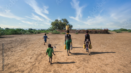 Fotomural Unidentified woman from Dassanech tribe carrying water to her village, Ethiopia