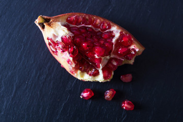 Wall Mural - natural ripe pomegranate on black slate background