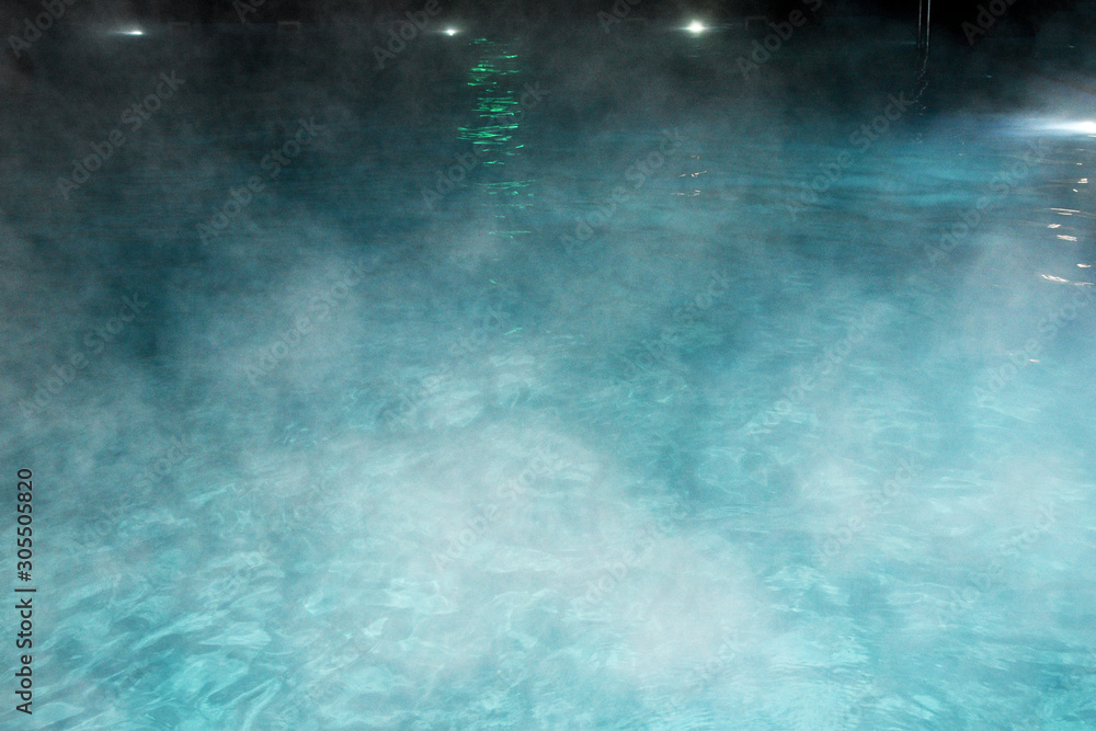 Pure clear water in the thermal pool. Hot water flows, and fog rises above the pool, the pool itself is illuminated by lanterns. Blue water, beautiful background. - obrazy, fototapety, plakaty 