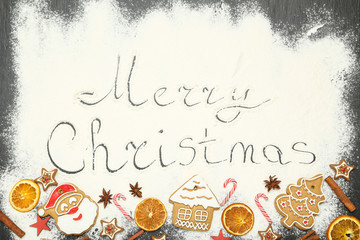 Wall Mural - Text Merry Christmas on flour with gingerbread cookies, dry oranges and candies