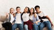 © Prostock-studio - Teen friends sitting on sofa and embracing, smiling to camera