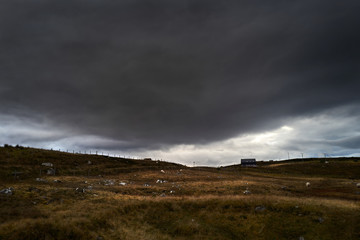 Poster - A distant isolated house under a dark stormy sky in the remote Scottish Highlands of Scotland in winter.