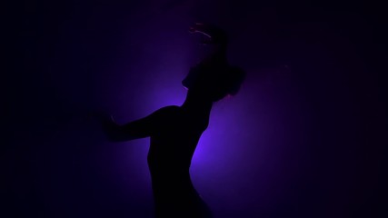 Wall Mural - Young beautiful ballerina on smoke stage dancing modern ballet. Performs smooth movements with hands against violet spotlight background. Woman in black tutu costume on scene. 4k