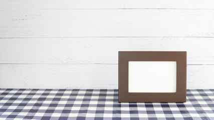 Old brown photo frame on table and white wooden background with copy space