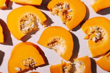 Slices of ripe pumpkin with seeds, white background.