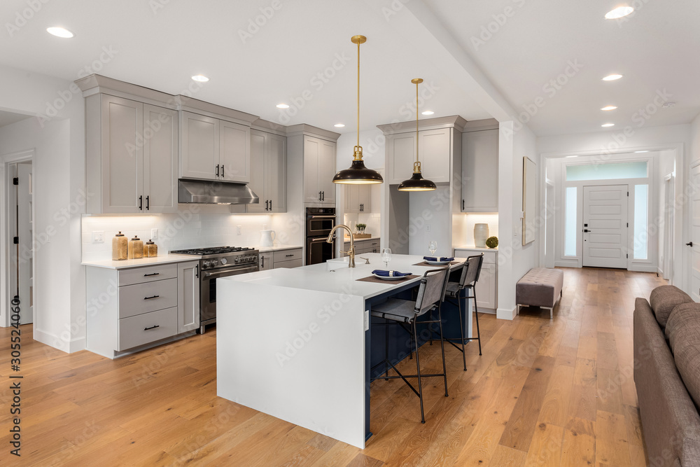 Beautiful kitchen in new luxury home with waterfall island, quartz counter tops, farmhouse sink, and hardwood floors. - obrazy, fototapety, plakaty 