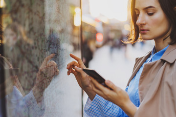 Young woman touching with finger screen while using train schedule application on mobile phone