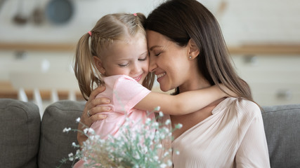 Wall Mural - Happy mom embracing kid daughter holding spring flowers bouquet