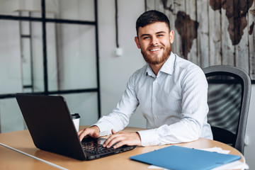 smiling, bearded man working on computer in office
